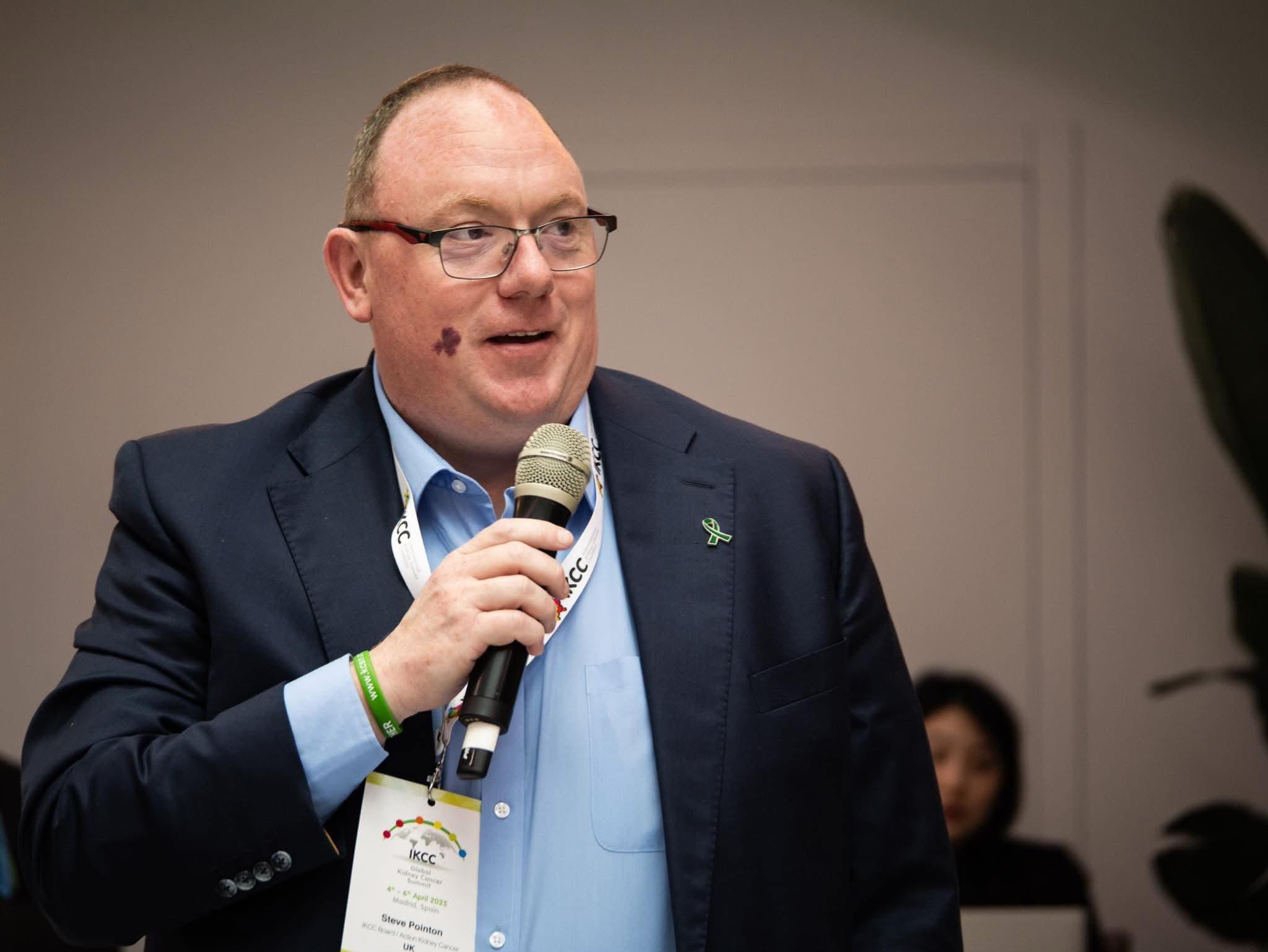 Steve Pointon speaking with a microphone at the IKCC Global Kidney Cancer Summit, Madrid 2025
